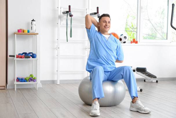 Male physiotherapist demonstrating exercise with fitball in rehabilitation center - Photo, Image