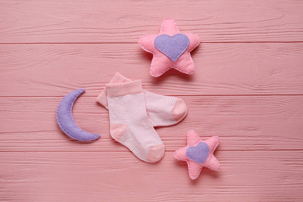 Baby sokken en speelgoed op kleur houten achtergrond - Foto, afbeelding