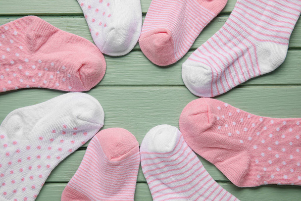 Frame made of different baby socks on color wooden background, closeup - Foto, Imagem