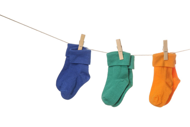Different baby socks hanging on rope against white background - Фото, зображення