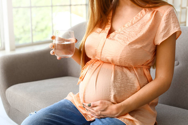 Young pregnant woman with glass of water at home - Photo, Image