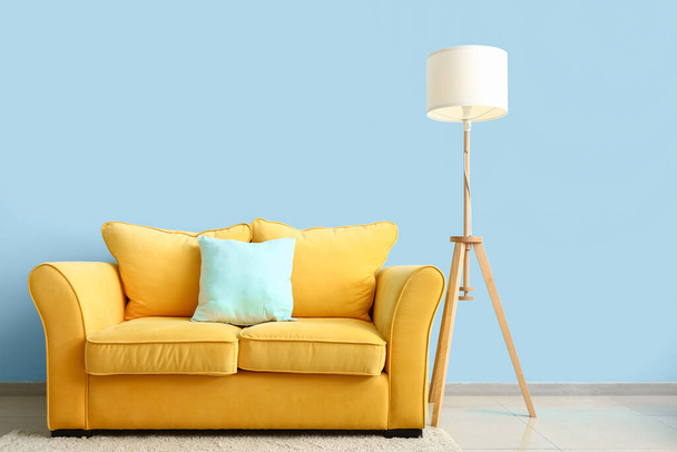 Cómodo sofá y lámpara moderna cerca de la pared de color - Foto, Imagen