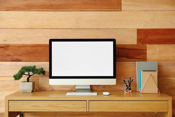 Σύγχρονος χώρος εργασίας με υπολογιστή κοντά σε ξύλινο τοίχο - Φωτογραφία, εικόνα