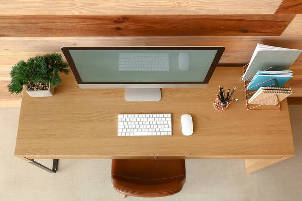 Moderno lugar de trabajo con ordenador cerca de pared de madera - Foto, imagen