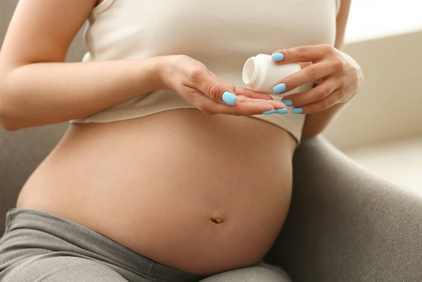 Mujer embarazada joven tomando pastillas en casa, primer plano - Foto, Imagen