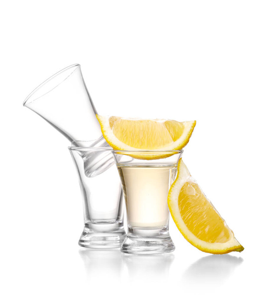 Ein Schuss leckerer Tequila mit Zitrone auf weißem Hintergrund - Foto, Bild