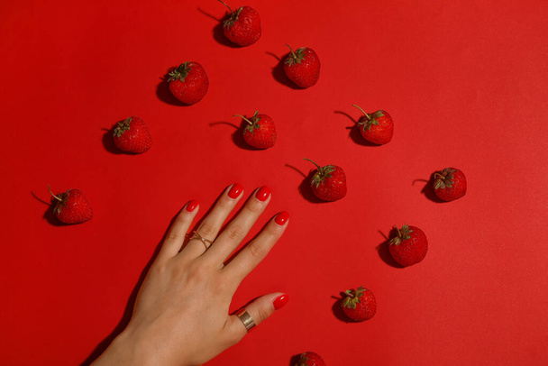 女性の手で美しいマニキュアとイチゴの色の背景 - 写真・画像