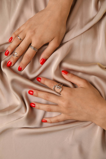 Female hands with beautiful manicure and jewelry on color fabric background - 写真・画像