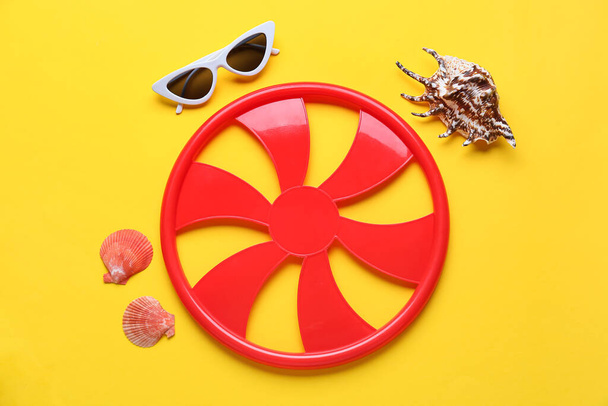 Δίσκος Frisbee, γυαλιά ηλίου και κοχύλια στο φόντο χρώμα - Φωτογραφία, εικόνα