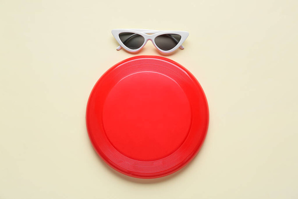 Frisbee-Scheibe und Sonnenbrille auf farbigem Hintergrund - Foto, Bild
