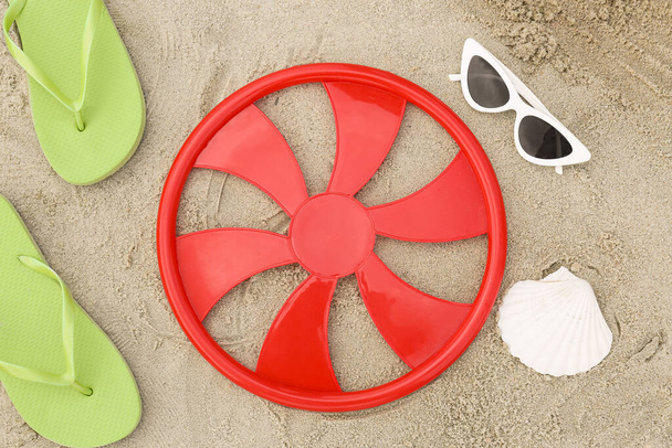 Δίσκος φρίσμπι, γυαλιά ηλίου και σαγιονάρες στην άμμο - Φωτογραφία, εικόνα