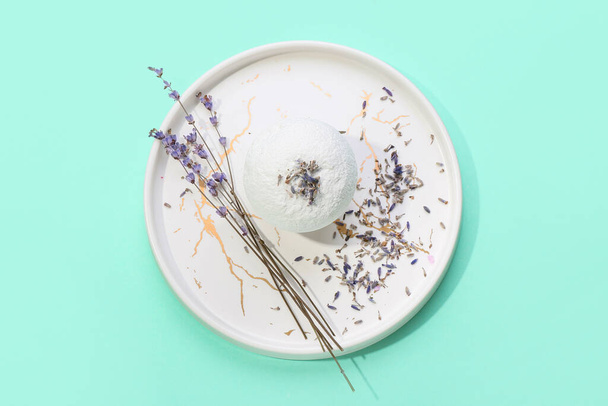 Teller mit Badebombe und Lavendelblüten auf farbigem Hintergrund - Foto, Bild