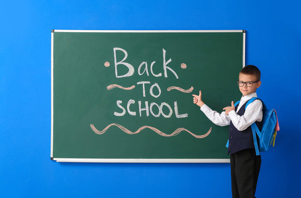 Schoolboy near blackboard on color background - Photo, Image