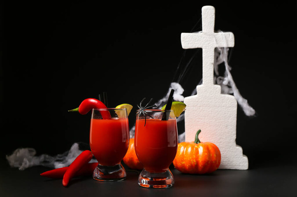 Vasos de sabroso cóctel sangriento María decorado para Halloween sobre fondo oscuro - Foto, imagen