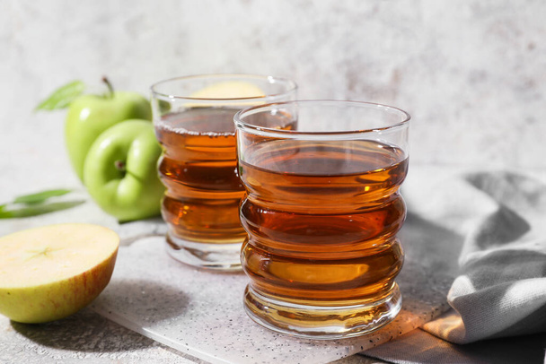Glasses of apple juice and fresh fruits on light background - Foto, afbeelding