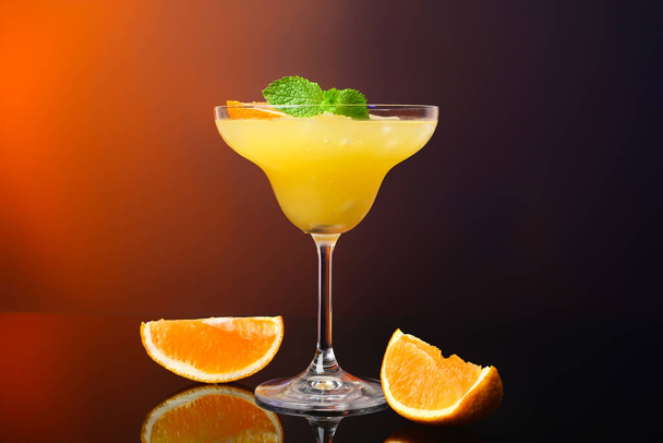 Glass of tasty orange margarita cocktail on dark color background - Photo, Image
