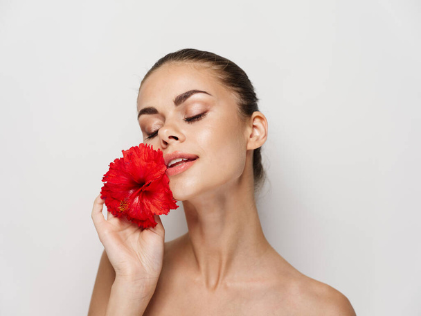 όμορφη γυναίκα γυμνοί ώμοι κόκκινο λουλούδι κλειστά μάτια γοητεία - Φωτογραφία, εικόνα