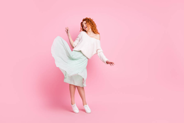 Longitud completa tamaño del cuerpo foto de la mujer de pelo rojo sonriendo en la falda de primavera baile feliz en la fiesta aislado sobre fondo de color rosa pastel - Foto, imagen