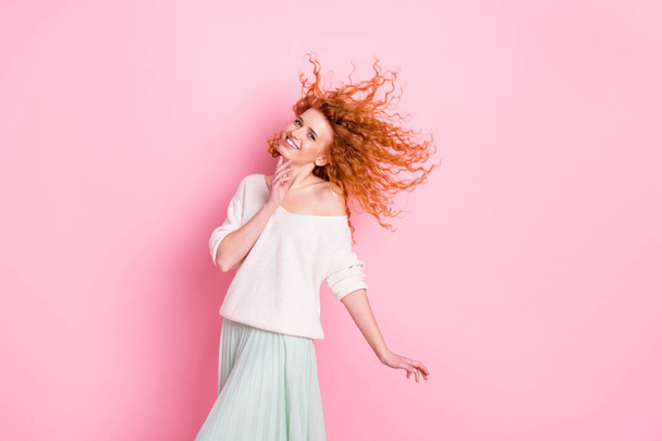 Portrait photo de jeune fille souriant cheveux volant dans l'air portant des vêtements élégants touchant cou isolé couleur rose pastel fond - Photo, image