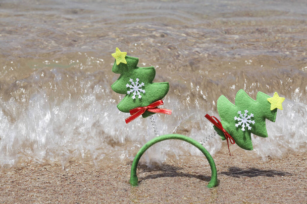 Natal e feliz ano novo conceito. Headband com árvores de Natal no fundo de areia perto do mar.  - Foto, Imagem