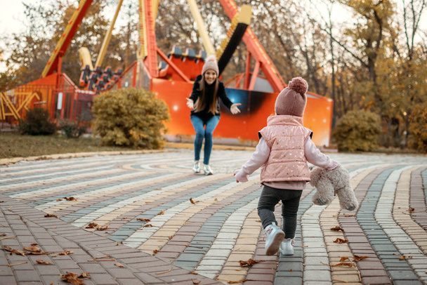 Mujer joven niñera y niña pequeña caminan en el parque de otoño. Feliz familia mamá y niño pequeño al aire libre en el parque de otoño. - Foto, Imagen