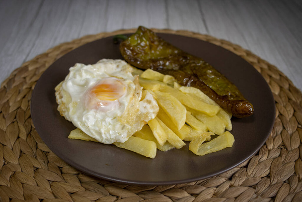 Жареный картофель с яичницей и жареным перцем, очень востребованная еда на юге Испании. Картофель не должен быть заморожен, и все домашнее. Сделано из оливкового масла. Вид спереди - Фото, изображение