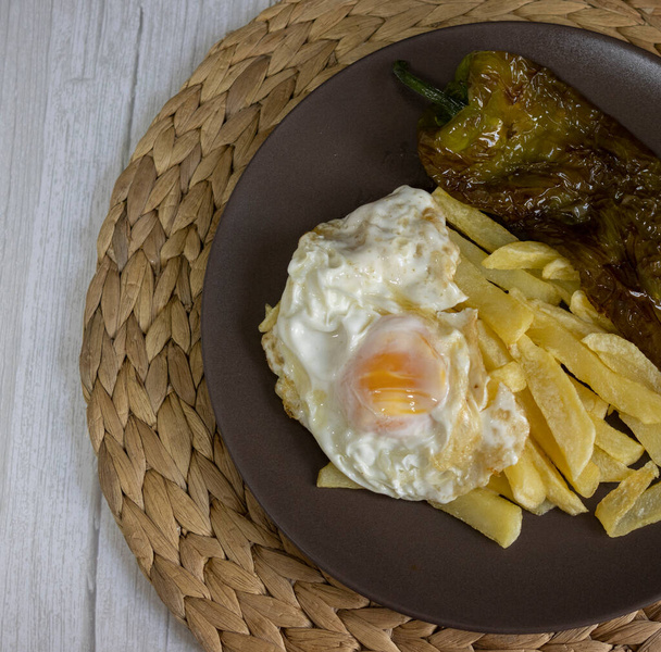 Sült krumpli tükörtojással és sült borssal, egy nagyon igényes étel Dél-Spanyolországban. A burgonyát nem szabad lefagyasztani, és házi készítésű. Mind olívaolajból készült. Felülnézet - Fotó, kép