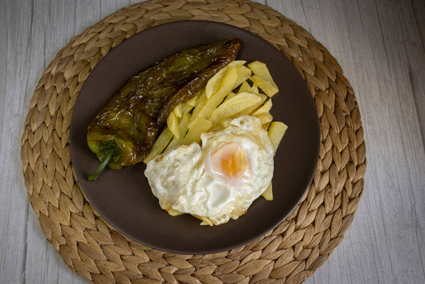 Жареный картофель с яичницей и жареным перцем, очень востребованная еда на юге Испании. Картофель не должен быть заморожен, и все домашнее. Сделано из оливкового масла. Вид сверху - Фото, изображение