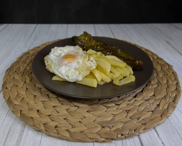 Smažené brambory se smaženým vejcem a smaženým pepřem, velmi žádané jídlo v jižním Španělsku. Brambory by neměly být zmrazené a všechny domácí. Vyrobeno z olivového oleje. Pohled zepředu - Fotografie, Obrázek
