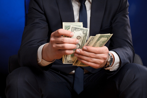Businessman counts money in hands. - Фото, изображение