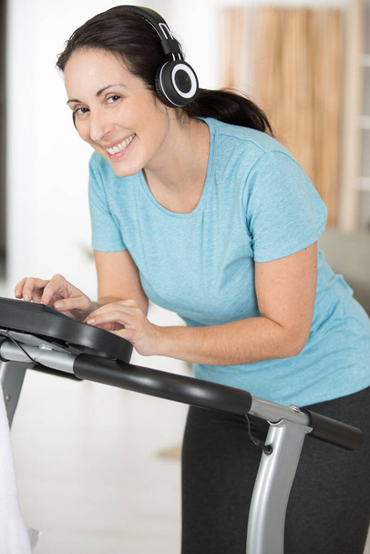 woman wearing headphones programming exercise machine - Photo, image