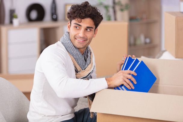 handsome bearded man in casual clothes packing books - Fotó, kép
