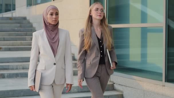 Serious purposeful colleagues Indian girl in hijab and young European woman go to office together. Confident diverse businesswomen completed deal, entered lucrative contract. Womens business concept - Footage, Video