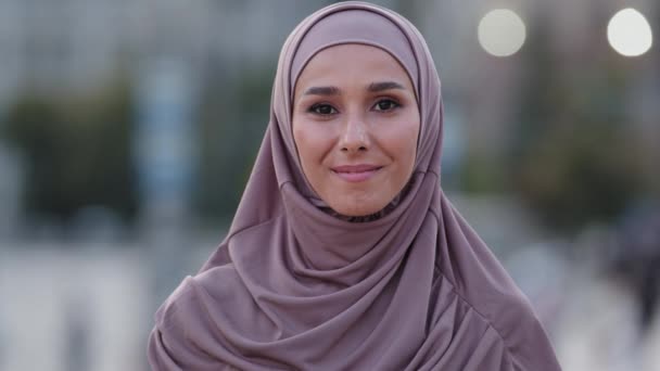 Nahaufnahme menschliches weibliches Gesicht Porträt muslimisches Mädchen jung freundlich lächelnd niedlich islamische Studentin Ausländer Kunde trägt Hijab Millennial arabische Dame im Freien stehen und in die Kamera lächeln zahm - Filmmaterial, Video