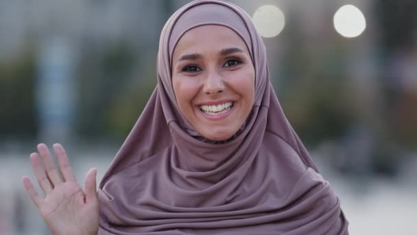 Vrouwelijk portret buiten islamitisch meisje jong volwassen moslim vrouw vriendelijk glimlachende dame student dragen beige hijab glimlach hallo hand begroeten praten praten online chat conferentie video oproep - Video