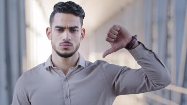 Close up male portrait hispanic bearded man arabic handsome serious businessman guy advisor unsatisfied client looking at camera showing thumb down gesture negative attitude disapproval bad assessment - Footage, Video
