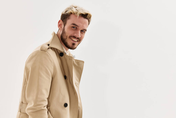 χαμογελαστός άνδρας σε μπεζ παλτό μόδα χτένισμα περικοπή στούντιο άποψη - Φωτογραφία, εικόνα