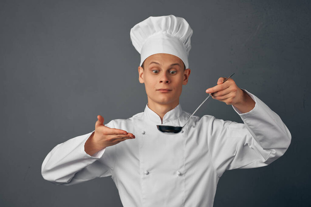 mężczyzna w mundurze kucharza z chochlą w ręku gotujący jedzenie profesjonalna kuchnia - Zdjęcie, obraz