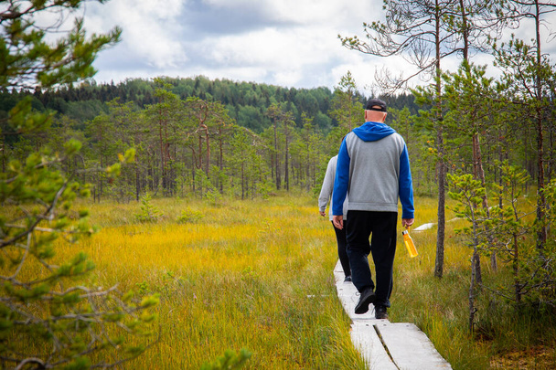 A closeup of people walking on a narrow path through the forest. - Valokuva, kuva