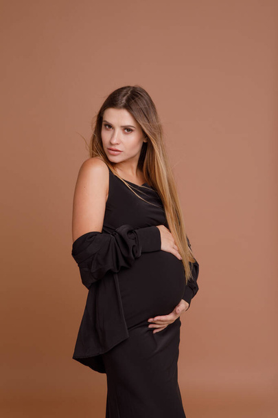 έγκυος γυναίκα στο στούντιο σε μπεζ φόντο - Φωτογραφία, εικόνα