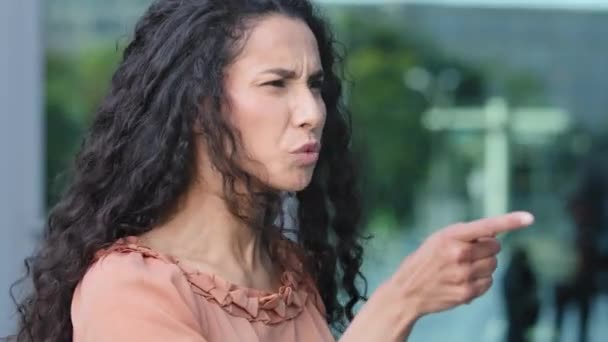 enojado agresivo negativo hispano joven mujer millennial molesto morena chica sintiendo irritado rabia furia gritos riña gesto con el dedo de pie en el perfil mirando a lado conflicto problema - Metraje, vídeo