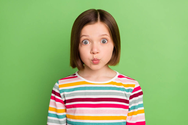 Photo of young little girl happy positive smile pouted lips amazed surprised isolated over green color background - Foto, afbeelding