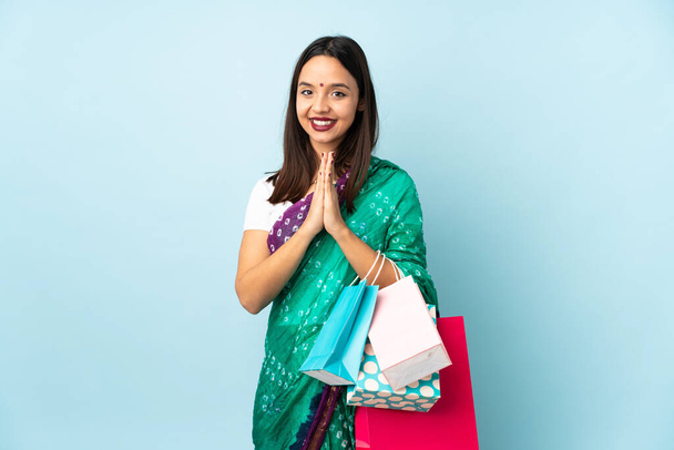 Mujer india joven con bolsas de compras mantiene la palma junta. Persona pide algo - Foto, Imagen