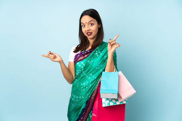 Young Indian woman with shopping bags pointing finger to the laterals and happy - Foto, Imagem