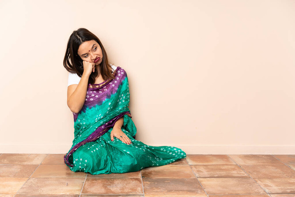 Young Indian woman sitting on the floor with tired and bored expression - Photo, Image