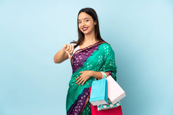 Young Indian woman with shopping bags showing thumb down with negative expression - Foto, Imagem