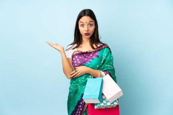 Young Indian woman with shopping bags making doubts gesture - Foto, Imagem