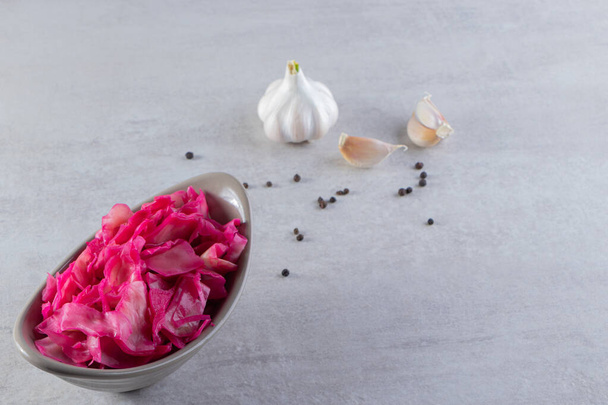 Pickled red cabbage with fresh garlic and pepper corns placed on stone table . High quality photo - Foto, imagen
