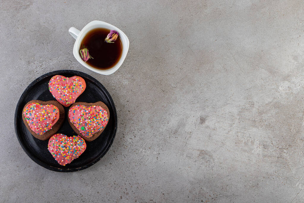 Kalbe serpiştirilmiş kurabiyeler ve taştan bir arka plana konmuş bir fincan çay. Yüksek kalite fotoğraf - Fotoğraf, Görsel
