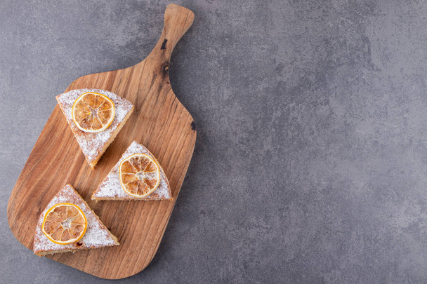 Кусочки торта с сушеными ломтиками лимона на каменном столе. Высокое качество фото - Фото, изображение